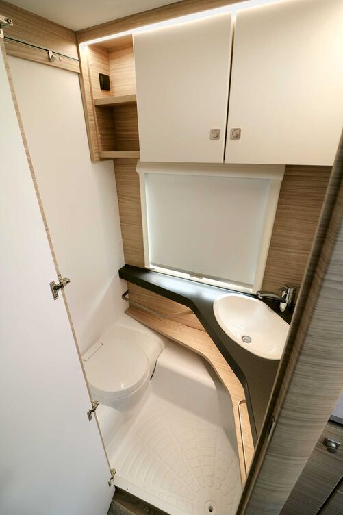 La salle de bains claire avec W. C. banc esthétique et lavabo placé dans l’angle offre tout l’essentiel malgré une surface compacte.