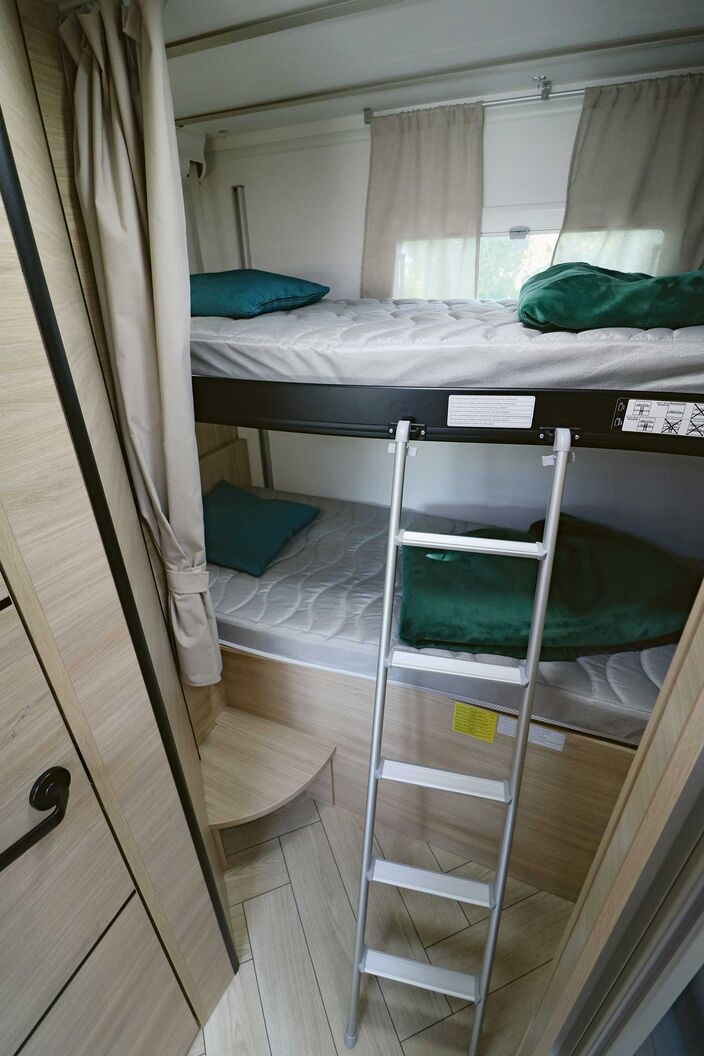 Je nach Platzbedarf kann das obere Etagenbett bis zur Decke positioniert oder per Elektroantrieb bis zur Mitte nach unten gefahren werden. Heckfenster und Vorhang komplettieren das Heckabteil.