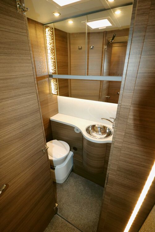 Im funktionalen Sanitärraum gefällt die Einrichtung mit dem beleuchteten Spiegelschrank und dem runden Edelstahlbecken.