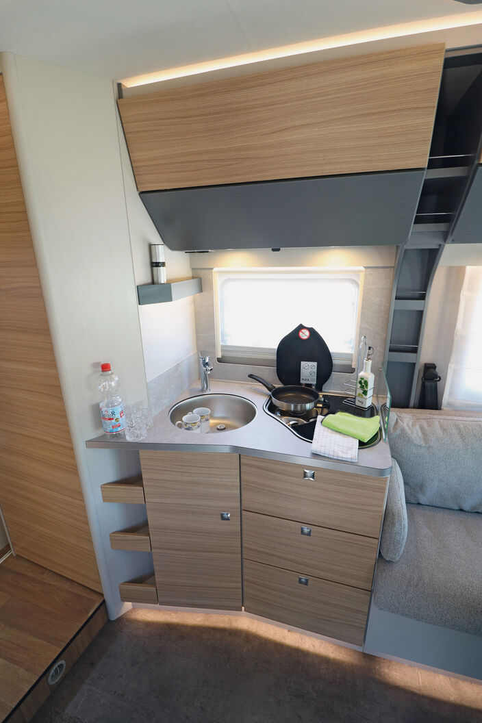 Die funktionale und gefällige Küche mit dem in Winkelform angedeuteten Unterschrank bietet ausreichend Stauraum und Arbeitsfläche.