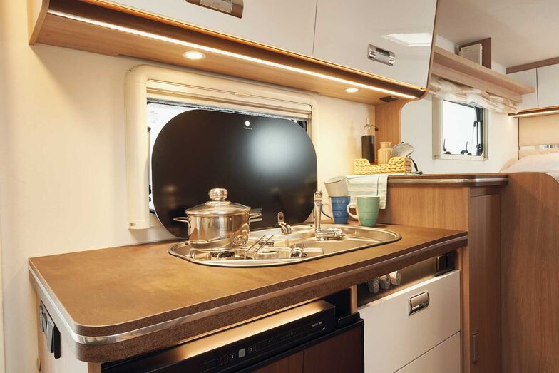 Bloc cuisine avec évier, plaque de cuisson trois feux et plan de travail.